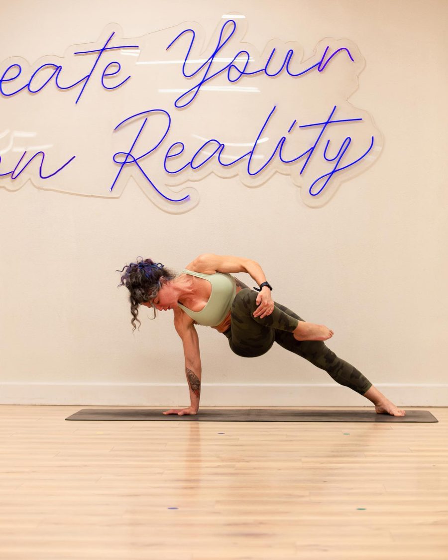 Dina Saad holding a side plank on a yoga mat in her studio